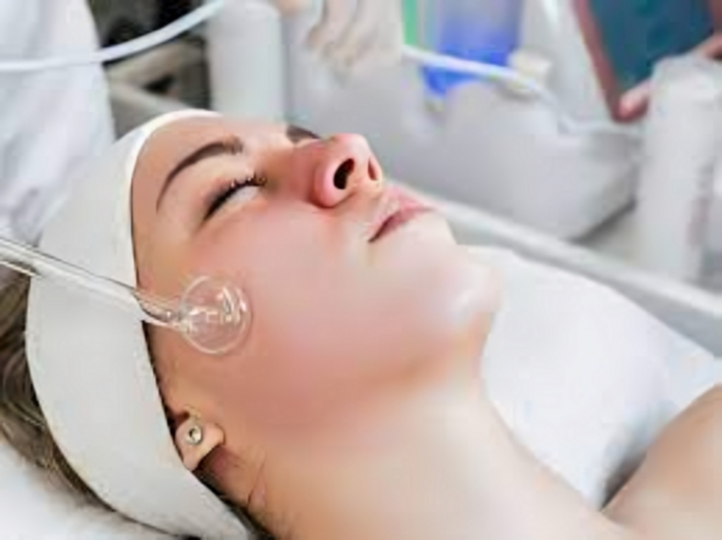 High frequency wand with glass electrode positioned over facial skin for skincare use